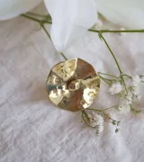 Anillo dorado con forma de flor con centro abultado y superficie texturizada.