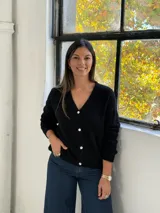 Saco tipo cardigan de punto color negro, con cuello en V, cierre frontal con botones y mangas largas con puños acanalados.
