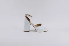 Sandalias de cuero blanco con plataforma y tacón cuadrado. Tienen pulsera al tobillo con hebilla.