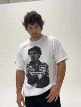 Remera blanca de algodón con estampa fotográfica frontal de Ayrton Senna con su traje de piloto de Fórmula 1. Presenta un corte holgado y cuello redondo.