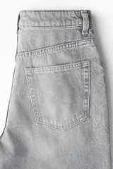 Jeans de cinco bolsillos en denim de algodón rígido, color gris claro lavado. Presenta un corte de cintura ultra alta, pierna amplia y recta desde la cadera hasta el bajo, con un estilo levemente largo.