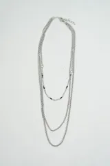 Collar plateado de tres cadenas de diferente grosor y largo, con eslabones pequeños y detalles de cuentas negras.