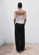 Pantalón wide leg de tiro medio color negro, con diseño largo, bolsillos laterales, bolsillos de ribete posteriores y detalle de pinzas. Cuenta con cierre oculto de botón, gancho y cremallera, e incluye forro interior.