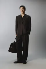 Blazer cruzada de hombre en color marrón oscuro, de corte regular fit, confeccionada en lino. Cuenta con solapas de muesca, bolsillos con solapa en la cadera y doble botonadura frontal.