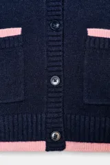 Chaqueta de punto de cuello redondo y manga larga, con cierre frontal de botones. Presenta dos bolsillos delanteros de plastrón y detalles de ribetes en color rosa a contraste en los puños, el ruedo y los bolsillos.