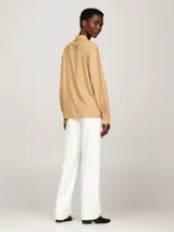 Camisa color beige de viscosa, de corte amplio, con cuello inglés, cierre frontal con botones y logo metálico de Tommy Hilfiger en la manga.
