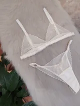 Conjunto de lencería compuesto por un corpiño triangular y una bombacha tipo tanga, confeccionados en encaje con diseño de ondas y terminaciones delicadas.