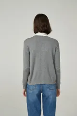 Cárdigan color beige con escote en V y cierre frontal con botones.