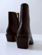 Bota de caña media confeccionada en cuero negro, con punta cuadrada y taco ancho de altura media.