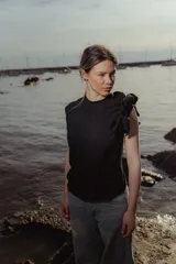 Top negro de punto con cuello redondo y volado en el hombro.