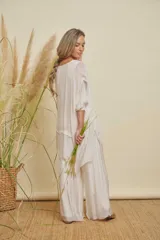 Conjunto de dos piezas color blanco, compuesto por una blusa holgada de manga 3/4 con capas asimétricas y un pantalón palazzo de tiro alto.