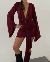 Vestido corto de color bordó, con diseño versátil de doble uso, permitiendo llevar el escote en la espalda o al frente. Presenta mangas largas acampanadas y un lazo regulable para ajustar el calce al cuerpo.