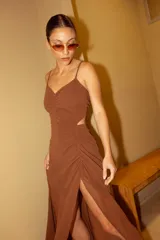 Vestido midi de crepé color fucsia, con escote corazón, tirantes finos cruzados en la espalda y aberturas laterales en la cintura. La falda presenta un diseño con frunces laterales y una abertura frontal que deja ver la pierna.