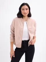 Campera tipo bomber de felpa en color beige, con cierre frontal completo, cuello, puños y ruedo acanalados en tono a juego.