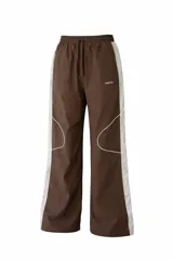 Pantalon de estilo deportivo color marron con paneles laterales en color crema y detalles de costuras blancas. Presenta cintura elastizada con cordón de ajuste y corte holgado.