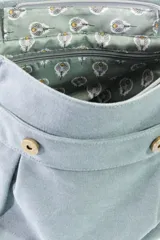 Mochila de lona estilo vintage con solapa frontal, bolsillos laterales y correas ajustables. Presenta detalles en cuero sintético y un parche decorativo en la parte superior.