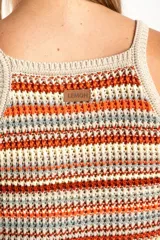 Top tejido de punto con diseño a rayas horizontales en tonos tierra, naranja y crema. Presenta un corte al cuerpo, escote halter y breteles finos.