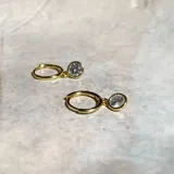 Aros dorados tipo argolla con dije colgante de circonia engarzada.