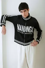 Campera tejida de algodón en color bordó y blanco, con cuello alto, cierre frontal completo y diseño con estampado tipográfico.
