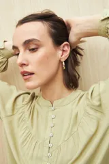 Camisa verde claro de viscosa suave, con cuello mao y botonadura parcial al frente. El detalle de frunces en los hombros y los puños abotonados le suman delicadeza y estilo.