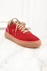 Zapatillas rojas de gamuza con cordones color beige y suela marrón. Detalle de animal print en el talón y pespuntes blancos.