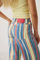 Pantalón wide leg de denim con diseño de rayas verticales multicolor en tonos amarillo, rojo y azul.