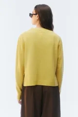Sweater de tejido de punto verde, con calce regular levemente suelto, escote redondo y mangas largas con puños acanalados.