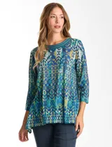 Blusa de calce relajado con estampado geométrico multicolor en tonos azules, verdes y amarillos. Presenta escote redondo con detalle tejido en el contorno, mangas tres cuartos y silueta levemente evasé.