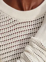 Sweater de punto calado color crema, de corte holgado y cuello redondo.