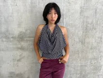 Top con escote halter y diseño drapeado, estampado con lunares blancos sobre fondo negro. Presenta espalda descubierta y cierre con botones en el cuello.