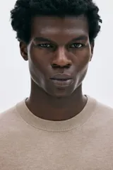 Buzo de punto fino color beige, con cuello redondo y manga larga, corte regular fit.