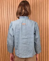Camisa de algodón color blanco, con cuello alto con volados, mangas tres cuartos con detalles de bordado ingles y cierre frontal con botones de nácar.