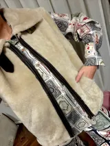 Chaleco de piel sintética en color chocolate, con cierre frontal y detalles de cuero en los bordes. Presenta un diseño de cuello solapa y ajuste lateral con hebillas.