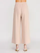 Pantalón palazzo de tiro alto color beige, confeccionado en mezcla de lino y viscosa, con silueta suelta y fluida, cintura elastizada, bolsillos delanteros aplicados y ruedo festoneado de corte tobillero.