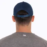 Gorra tipo trucker color azul, con panel frontal y visera de tela técnica, paneles laterales y traseros de malla transpirable. Presenta un parche circular bordado en el frente con el logo de la marca y diseño de montaña.