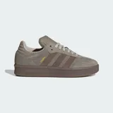Championes Adidas modelo Samba XLG, con diseño de silueta rediseñada con mayor profundidad. Presentan exterior de cuero y gamuza en tonos gris y marrón, con las icónicas tres tiras laterales y suela de caucho robusta. Incluyen lengüeta acolchada y detalles en dorado.