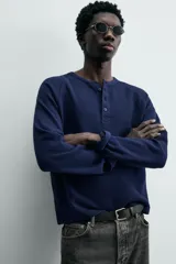 Camiseta de manga larga con cuello redondo y cierre frontal de botonadura tipo henley, confeccionada en tejido de punto con textura waffle.