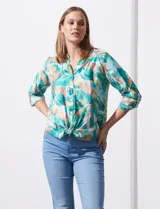 Blusa estampada de seda fría marca Figueroa & Flower. Tiene cuello a la base y escote en V, detalle de diferente estampa en hombros y espalda, apertura central con botones de nácar, mangas 3/4 regulables con presilla y botón, y terminación de ruedo con nudo.
