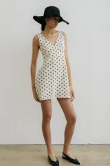 Vestido corto color crema con estampado de lunares negros, escote en V y sin mangas.