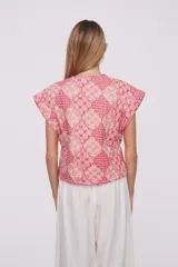 Chaleco corto con estampado geométrico en tonos rosa y rojo, sin mangas y cuello redondo.