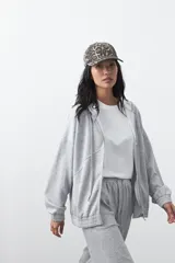 Campera con capucha y cierre frontal, de silueta relajada, hombros caídos y bolsillos laterales. Presenta terminaciones elastizadas en puños y ruedo, con líneas de recorte frontales y cierre metálico con tirador circular.