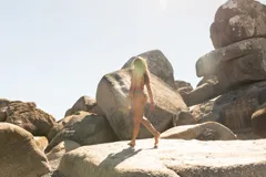 Conjunto de bikini compuesto por un top triangular y una bombacha de atar en los laterales. Presenta un estampado de conchas marinas en color rosado sobre una base de color verde.