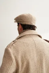 Boina con visera de lana fina uruguaya natural, sin teñir, con diseño de tejido texturizado en tonos beige y marrón.