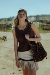 Minifalda color crema de cuero ovino con flecos y detalles en cuero marrón. Cierre frontal con cremallera. Estilo country.