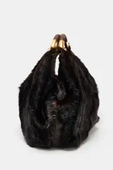 Maxi bolso de mano con acabado de pelo sintético en color marrón oscuro. Presenta un diseño estructurado con doble asa de mano reforzada y detalles metálicos dorados en las uniones. Cuenta con cierre mediante botón imantado y forro interior con bolsillo con cremallera.