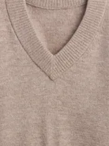 Buzo de punto con cuello en V, manga larga y puños acanalados. Diseño holgado y minimalista.