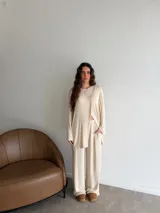 Conjunto de dos piezas color gris melange, confeccionado en tela de lanilla, compuesto por un buzo de manga larga con diseño cruzado al frente y un pantalón largo de corte holgado y tiro alto.