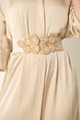 Cinto elástico color beige con hebilla metálica formando hojas con mostacillas.