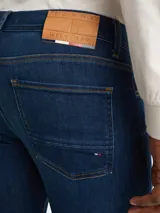 Jeans de denim azul oscuro con efecto desteñido en la parte delantera, corte ajustado, cierre de cremallera con botón y diseño de cinco bolsillos.