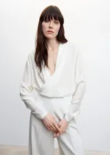 Blusa blanca de escote cruzado drapeado, manga larga y diseño recto.